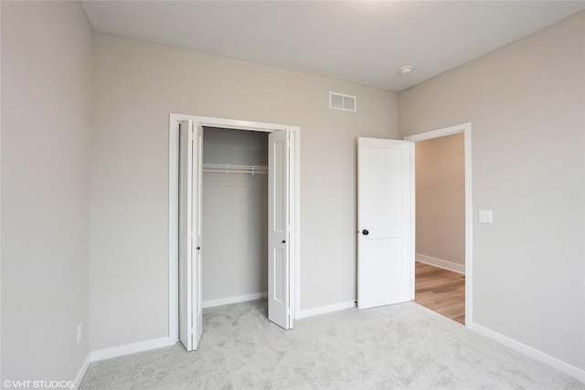 unfurnished bedroom featuring visible vents, carpet flooring, baseboards, and a closet
