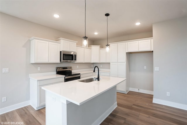 kitchen with wood finished floors, baseboards, white cabinetry, a sink, and appliances with stainless steel finishes