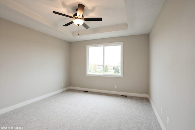 empty room featuring carpet floors, a ceiling fan, baseboards, and visible vents