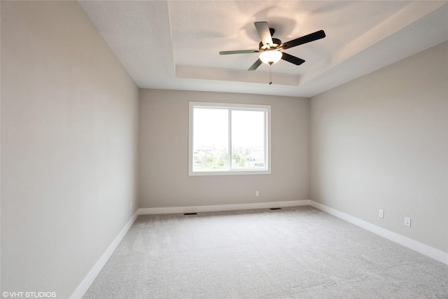 spare room featuring baseboards, carpet flooring, ceiling fan, and a tray ceiling