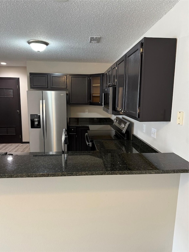 kitchen with appliances with stainless steel finishes, kitchen peninsula, and a textured ceiling