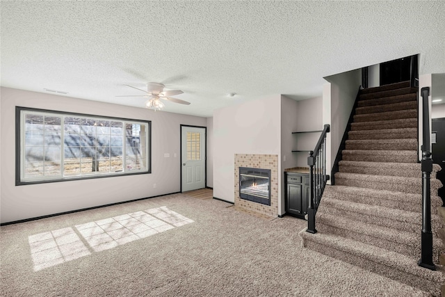 unfurnished living room featuring visible vents, stairway, a tiled fireplace, light carpet, and baseboards