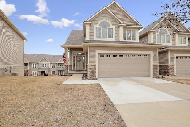 14102 Ridgemont Dr, Urbandale, IA 50323 - view of front facade with concrete driveway, an attached garage, stone siding, and a shingled roof