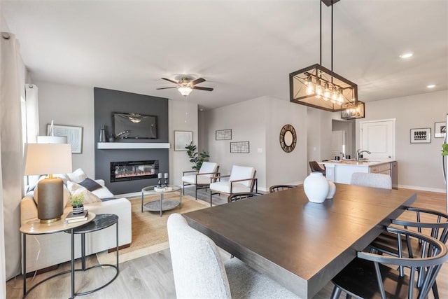 dining room with ceiling fan, sink, and light wood-type flooring