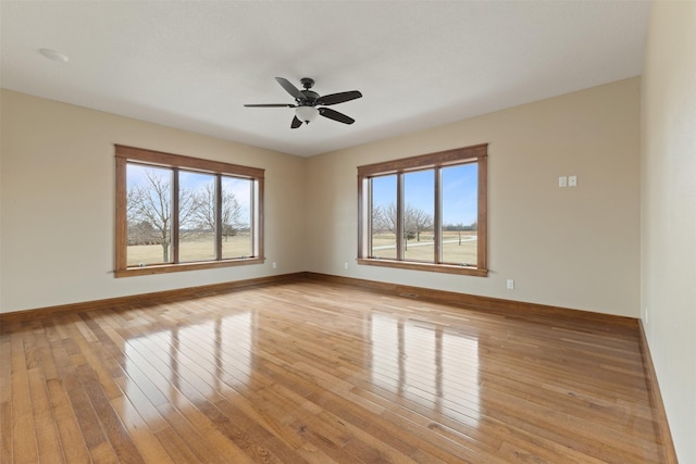 empty room with ceiling fan and light hardwood / wood-style flooring