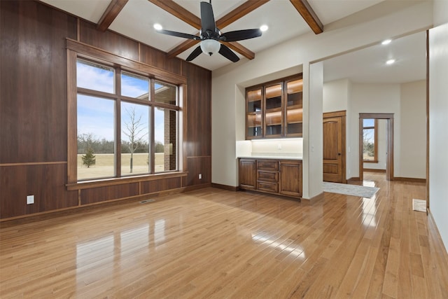 interior space with coffered ceiling, light hardwood / wood-style flooring, wooden walls, beamed ceiling, and ceiling fan