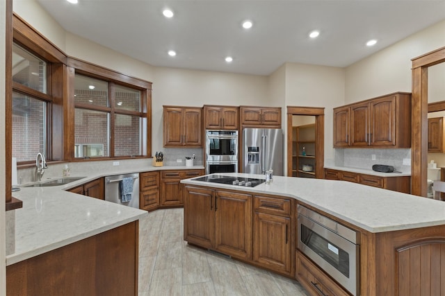 kitchen with sink, tasteful backsplash, a kitchen island, stainless steel appliances, and light stone countertops