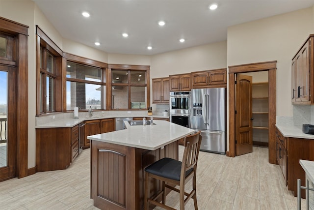 kitchen with a kitchen island, appliances with stainless steel finishes, a breakfast bar, sink, and backsplash