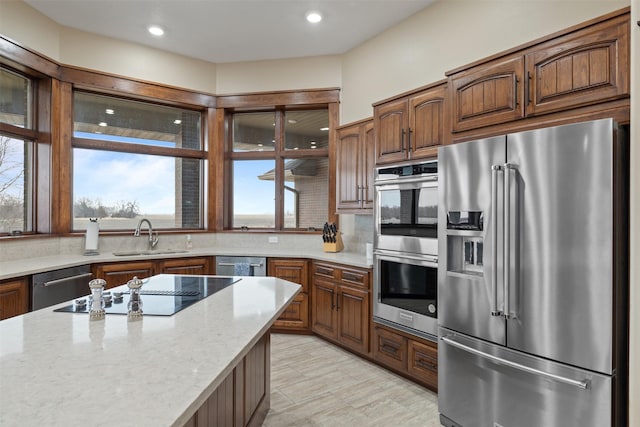 kitchen with light stone counters, stainless steel appliances, sink, and decorative backsplash