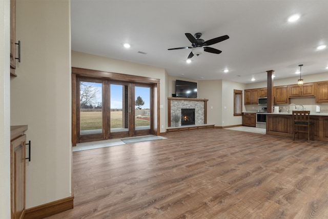 unfurnished living room featuring light hardwood / wood-style flooring, a fireplace, and ceiling fan