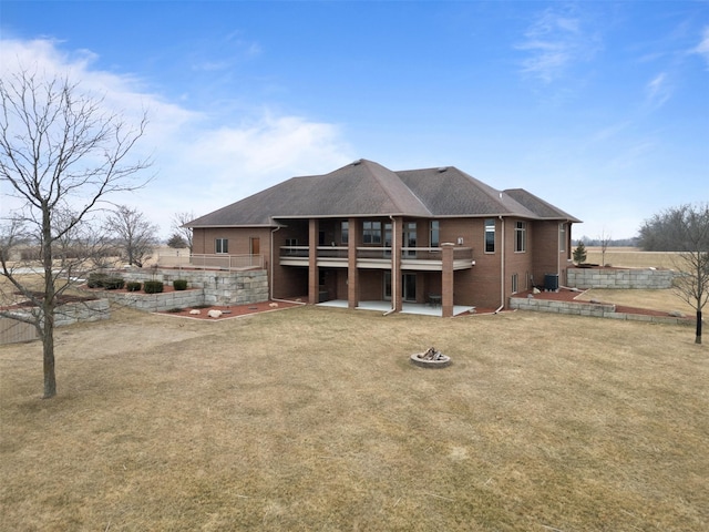 back of property featuring a balcony, a patio, and a lawn