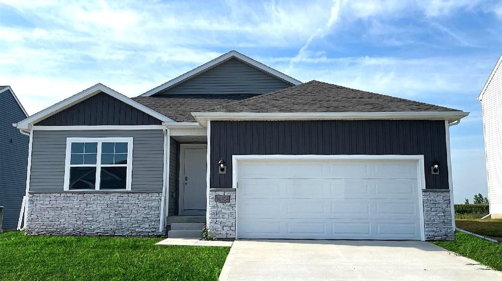 2409 Chan Dr, Adel, IA 50003 - view of front facade featuring driveway, a shingled roof, an attached garage, and stone siding