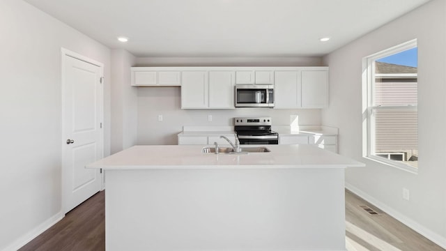 kitchen with sink, white cabinetry, a center island with sink, appliances with stainless steel finishes, and hardwood / wood-style flooring