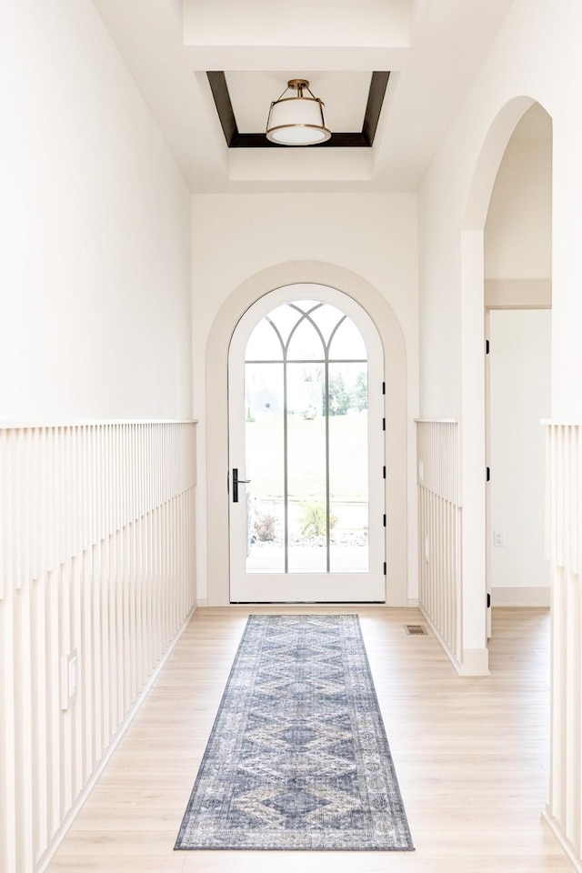 doorway featuring a raised ceiling and light hardwood / wood-style flooring