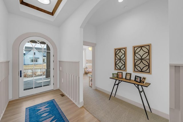 doorway featuring a towering ceiling and light hardwood / wood-style floors