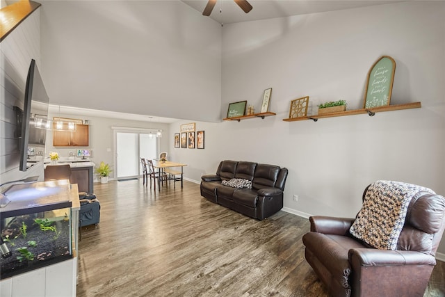 living room with wood-type flooring, ceiling fan, and a high ceiling