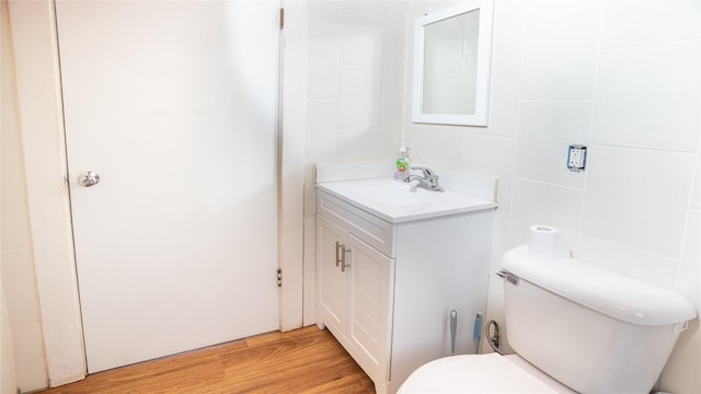 bathroom featuring hardwood / wood-style flooring, vanity, toilet, and tile walls