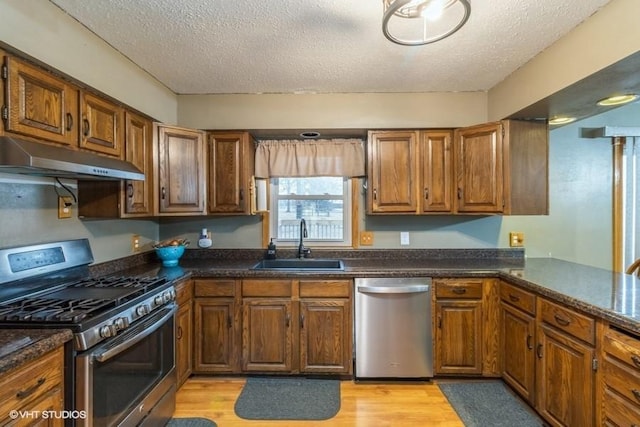 kitchen with sink, light hardwood / wood-style flooring, a textured ceiling, and appliances with stainless steel finishes