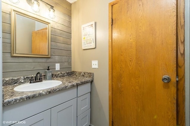 bathroom with vanity and wood walls