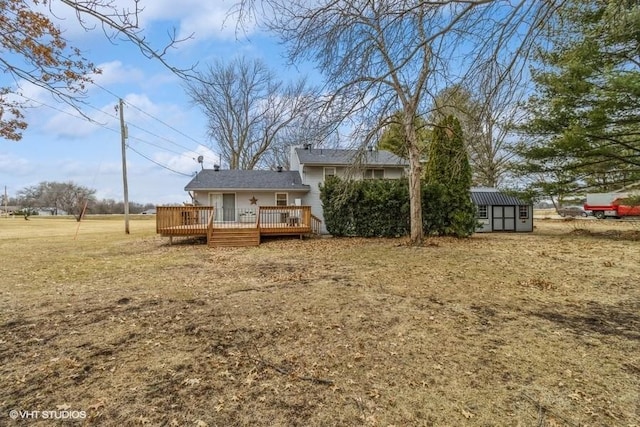 rear view of house with a yard, a deck, and a storage shed