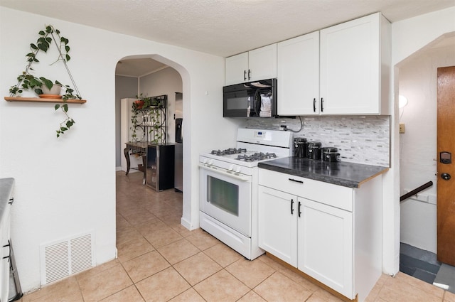 kitchen featuring white cabinetry, white gas stove, decorative backsplash, and light tile patterned floors