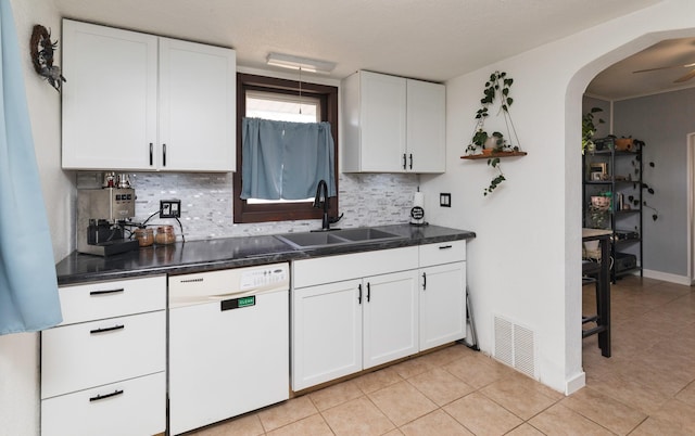 kitchen with sink, white cabinetry, light tile patterned floors, dishwasher, and decorative backsplash