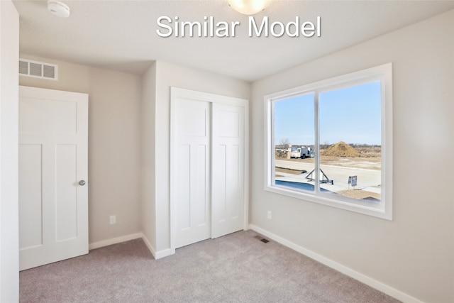 unfurnished bedroom with baseboards, a closet, visible vents, and light colored carpet