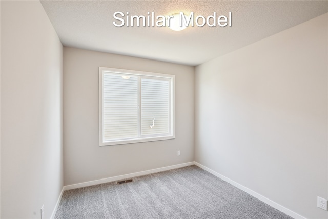 carpeted empty room with a textured ceiling