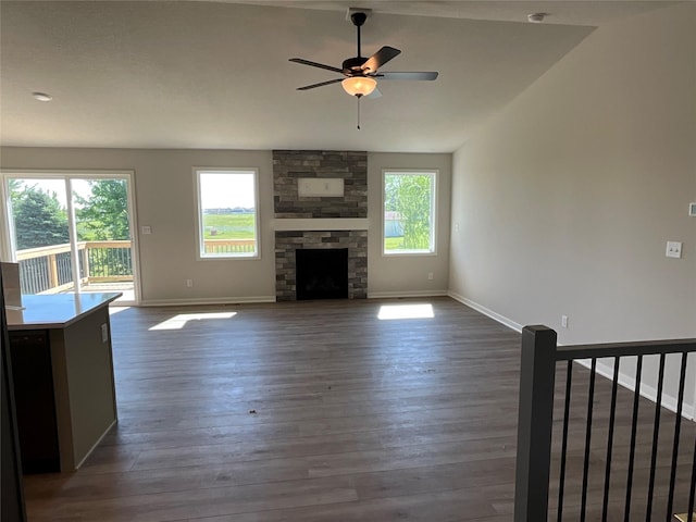 3423 5th Ave SE, Altoona, IA 50009 - unfurnished living room featuring a ceiling fan, baseboards, dark wood-type flooring, a stone fireplace, and lofted ceiling