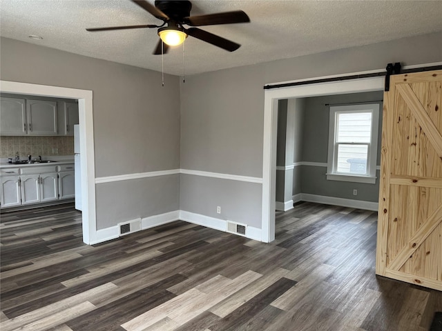 interior space featuring dark hardwood / wood-style flooring, sink, a barn door, and a textured ceiling