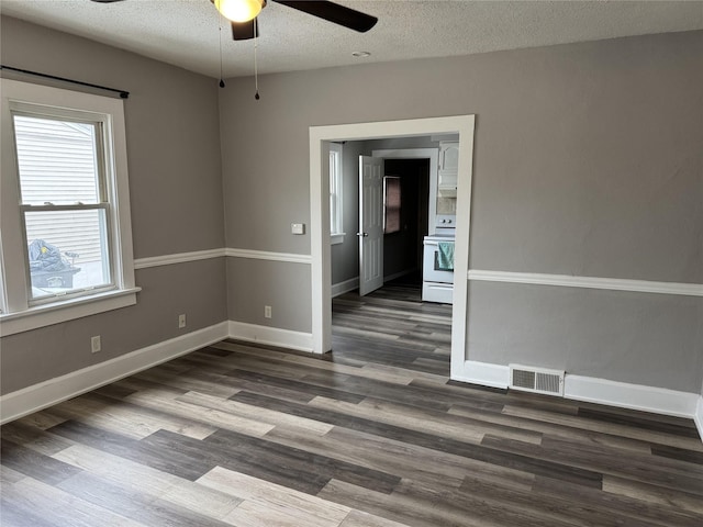 empty room featuring ceiling fan, dark wood-type flooring, and a textured ceiling