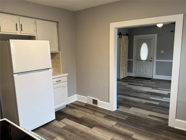 kitchen featuring white cabinetry, tasteful backsplash, white refrigerator, dark hardwood / wood-style flooring, and a barn door