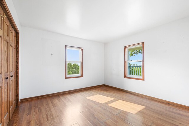 2466 655th Ave, Albia, IA 52531 - unfurnished bedroom with multiple windows, a closet, light wood-style flooring, and baseboards