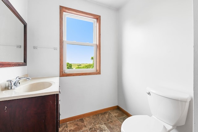 2466 655th Ave, Albia, IA 52531 - half bathroom featuring baseboards, plenty of natural light, toilet, and vanity