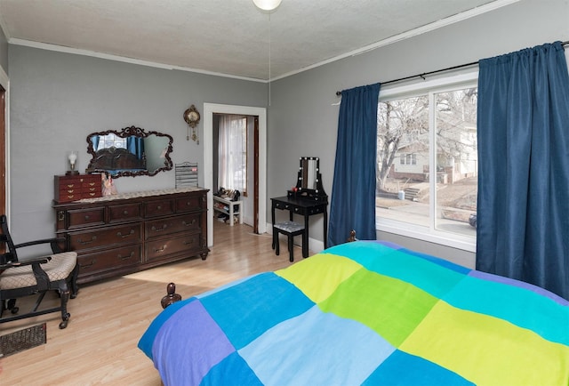 bedroom with ornamental molding, a textured ceiling, and light hardwood / wood-style floors