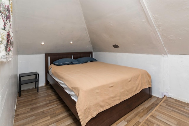 bedroom with wood-type flooring and vaulted ceiling