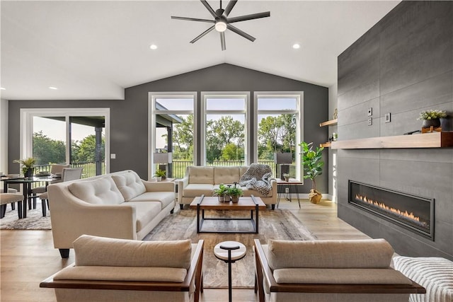 living room featuring lofted ceiling, a fireplace, and light wood-type flooring