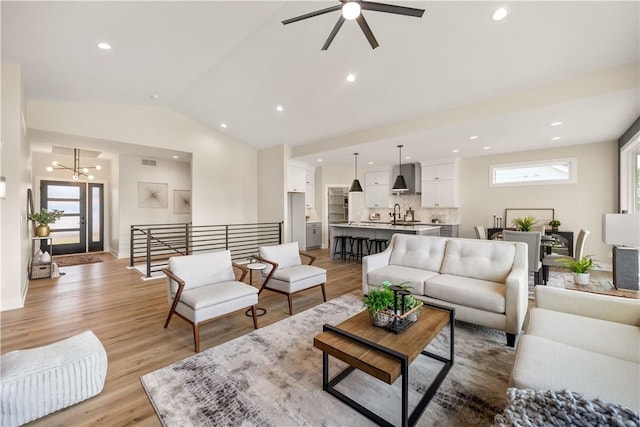 living room featuring lofted ceiling, sink, an inviting chandelier, and light wood-type flooring