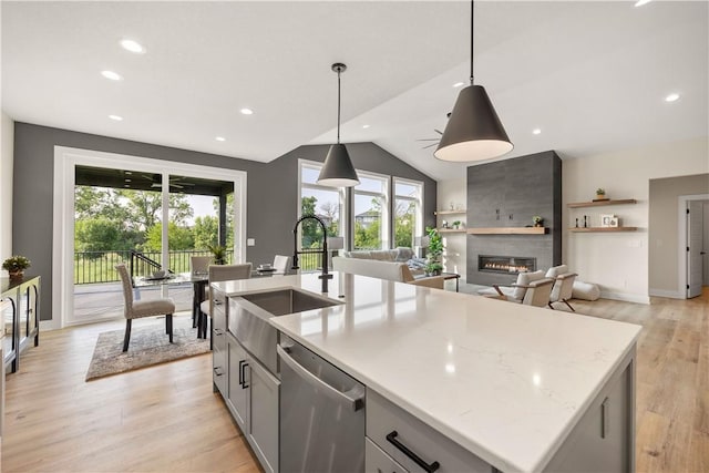 kitchen featuring pendant lighting, sink, a kitchen island with sink, light stone countertops, and stainless steel dishwasher