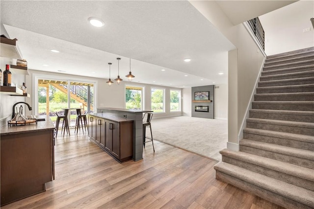 kitchen featuring pendant lighting, dark brown cabinets, a center island, and a healthy amount of sunlight