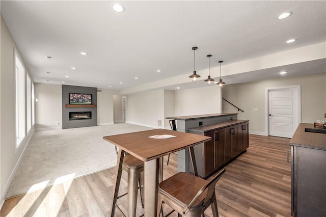 kitchen featuring sink, hanging light fixtures, dark brown cabinets, a fireplace, and light hardwood / wood-style floors