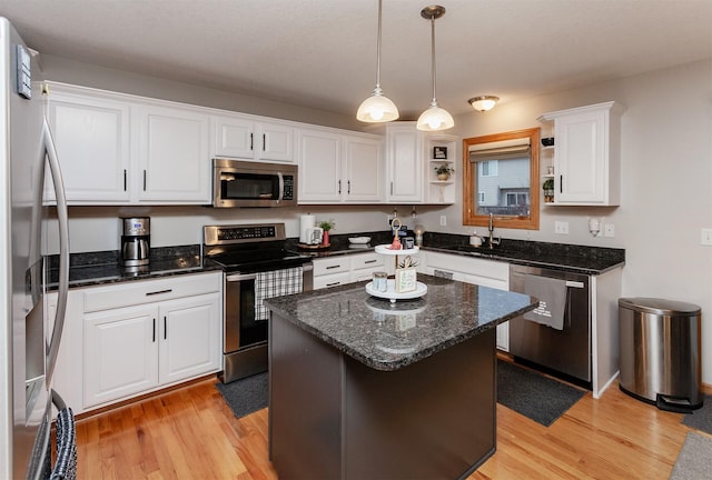 kitchen with white cabinetry, dark stone counters, a center island, light hardwood / wood-style floors, and stainless steel appliances