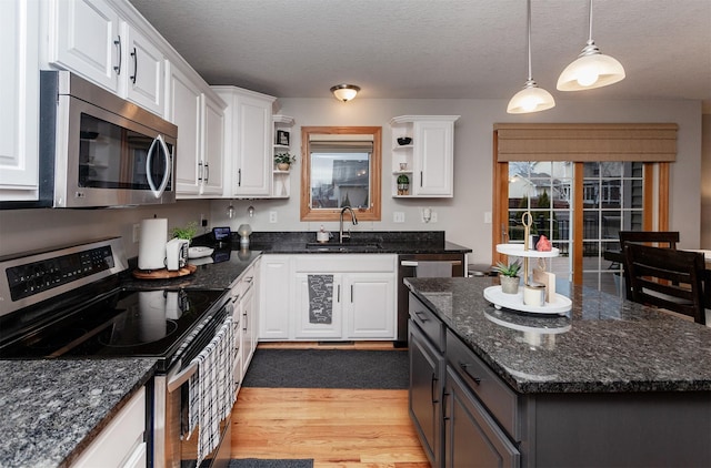 kitchen with sink, white cabinetry, decorative light fixtures, dark stone countertops, and appliances with stainless steel finishes