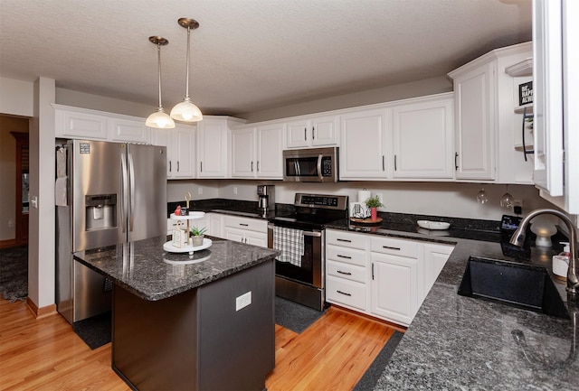 kitchen featuring sink, hanging light fixtures, a kitchen island, stainless steel appliances, and white cabinets