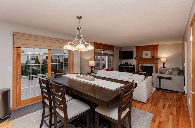 dining room with a fireplace, light hardwood / wood-style floors, and a chandelier