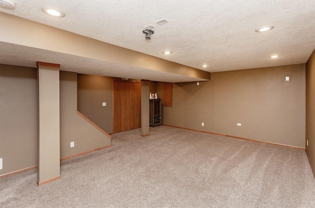 basement featuring light carpet and a textured ceiling