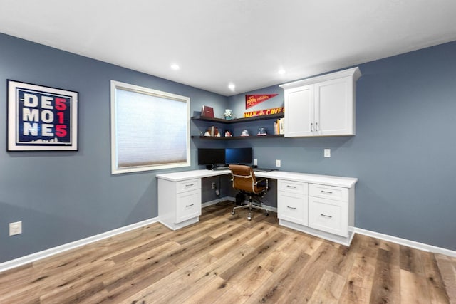 home office with built in desk and light hardwood / wood-style floors