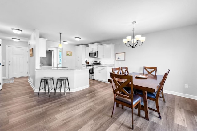 dining area with sink, hardwood / wood-style floors, and a notable chandelier