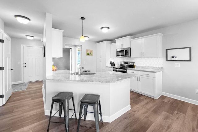 kitchen with white cabinetry, hanging light fixtures, kitchen peninsula, stainless steel appliances, and light stone countertops