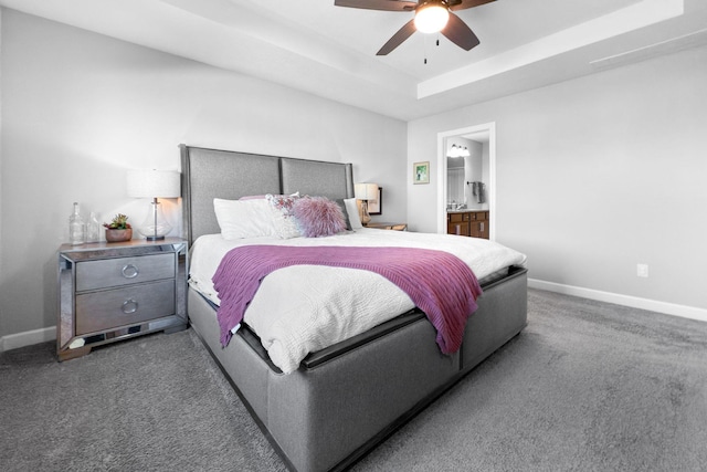 carpeted bedroom with a raised ceiling, ceiling fan, and ensuite bath